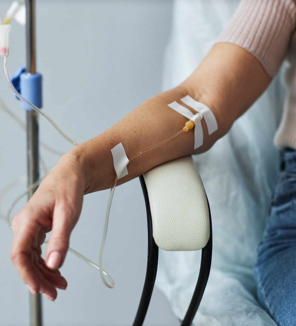 Closeup of female hand with IV drip infusion in treatment session at hospital, copy space
